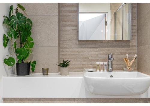 ein Badezimmer mit einem weißen Waschbecken und einem Spiegel in der Unterkunft Cosmopolitan Living: Upscale 1BR Gem in Beckenham in Beckenham