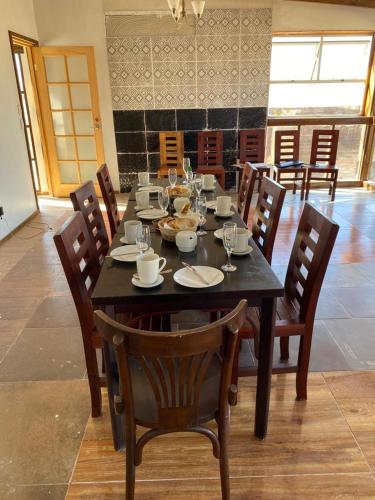 a dining room table with chairs and a black table with glasses at Eco Lodge Lorotuerto de Guanaqueros in Coquimbo