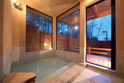 bañera en una habitación con ventanas y banco en 湯音の森 en Kusatsu