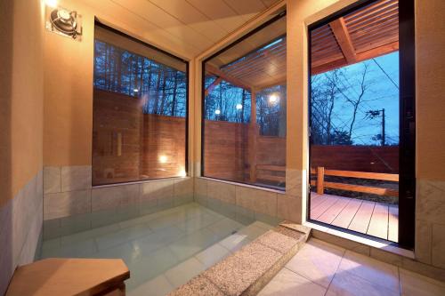 a tub in a room with windows and a bench at 湯音の森 in Kusatsu
