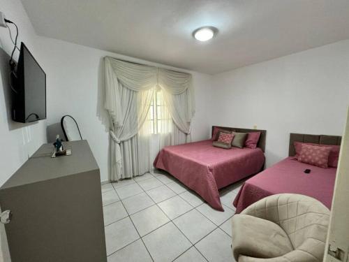 1 dormitorio con 2 camas con sábanas rosas y TV en Casa de Campo Monte Sião, en Monte Sião
