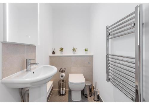 uma casa de banho branca com um lavatório e um WC em Designer Flat in Prime Location em Beckenham