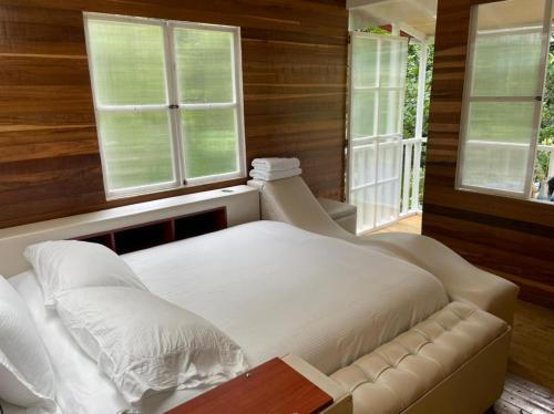 1 dormitorio con 1 cama blanca y 2 ventanas en Villas del Rio Glamping, en San Francisco