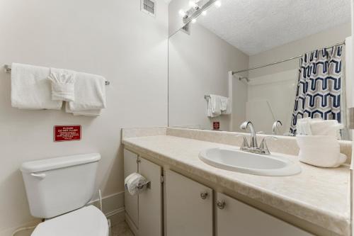 a bathroom with a sink and a toilet and a mirror at Top of the Gulf 523 - Beach Front Resort With Ocean View in Panama City Beach