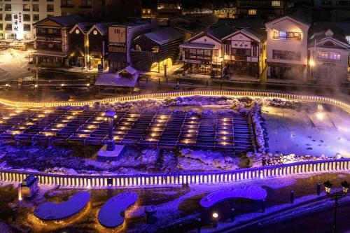 草津温泉、スキー場、湯畑、熱帯圏車で5分以内！最大27人宿泊可能 في كوساتسو: إضاءة المدينة في الليل مع أضواء أرجوانية