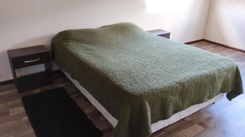 uma cama com um cobertor verde e uma mesa de cabeceira em Jade 1840 casa completa em San Carlos de Bariloche
