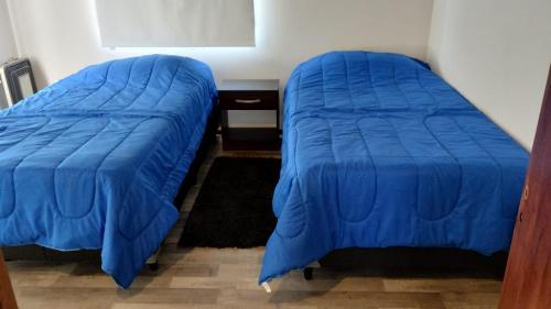 2 camas con colchas azules en una habitación en Jade 1840 casa completa en San Carlos de Bariloche