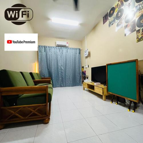 uma sala de estar com um sofá verde e uma televisão em Jalan Sena Indahpura Landed House em Kulai
