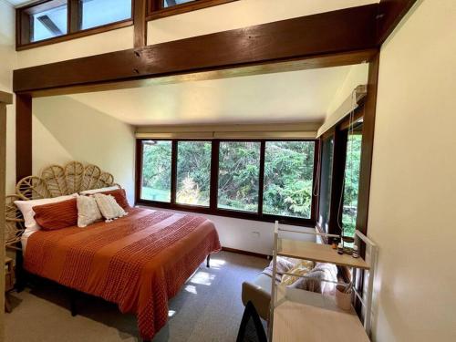 a bedroom with a bed in a room with windows at Heartwood Hill in Uki