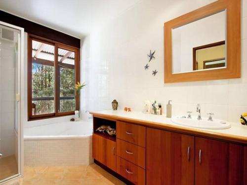 ein Badezimmer mit einer Badewanne, einem Waschbecken und einem Spiegel in der Unterkunft Heartwood Hill in Uki