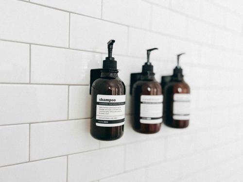 three bottles of liquid on a wall in a bathroom at Cozy Coastal Bungalow in Opelika