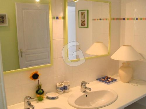 La salle de bains est pourvue d'un lavabo, d'une lampe et d'un miroir. dans l'établissement Maison 4 pers avec jardin privé et parking, proche mer - Angles - FR-1-357-6, à Angles