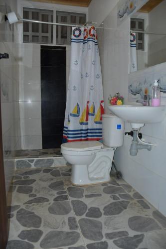 ein Badezimmer mit einem WC, einem Waschbecken und einem Duschvorhang in der Unterkunft Hacienda Mi Rancho in Villavicencio