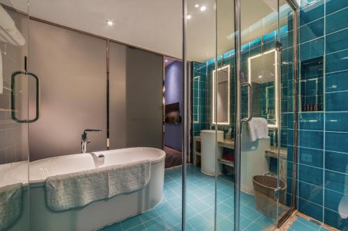 a bathroom with a tub and a shower with blue tiles at Nanxianglou Art Hotel in Shenzhen