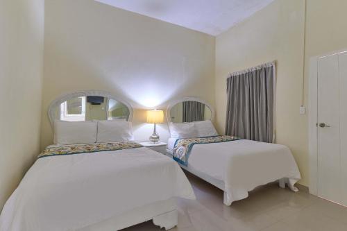a bedroom with two beds and a mirror at Hotel D'Cornelio in Santo Domingo