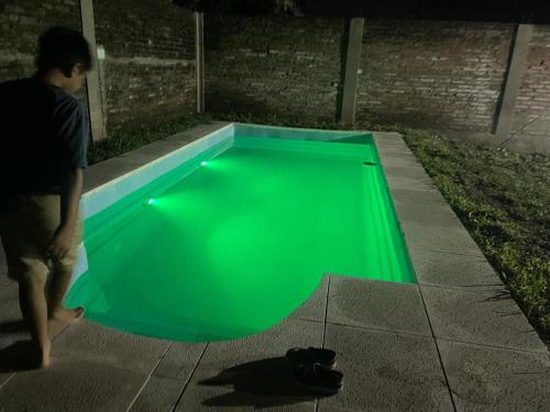 ジェルバ・ブエナにあるLO DE TINの緑のスイミングプールの横に立つ男