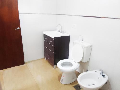 a bathroom with a white toilet and a sink at House, Summer in Villa Gesell