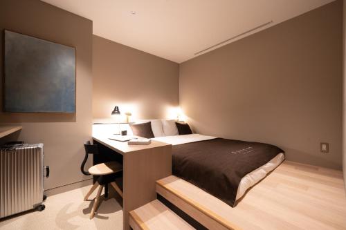 東京的住宿－CAFE/MINIMAL HOTEL OUR OUR，一间卧室配有一张床、一张桌子和一张四柱床。