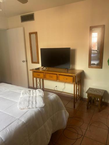 a bedroom with a bed and a desk with a television at Depa a unos minutos de consulado! in Hermosillo