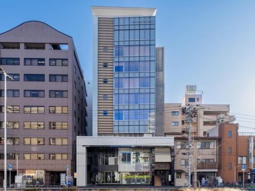 um edifício alto em frente a alguns edifícios em The OneFive Sendai em Sendai