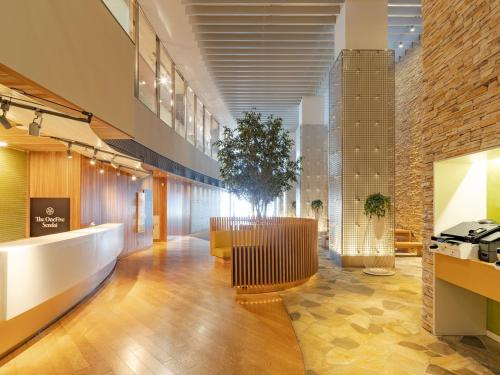 a lobby of a building with a tree in the middle at The OneFive Sendai in Sendai