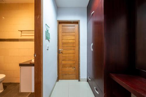 a bathroom with a toilet and a wooden door at The Kutaya in Kuta