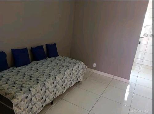 a bedroom with a bed with blue pillows on it at Casa a 5 km de Luziânia 1 quarto com ar-condicionado in Cidade Ocidental