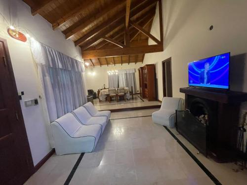 ein Wohnzimmer mit weißen Möbeln und einem Flachbild-TV in der Unterkunft La casa de Cate in Mar de Ajó