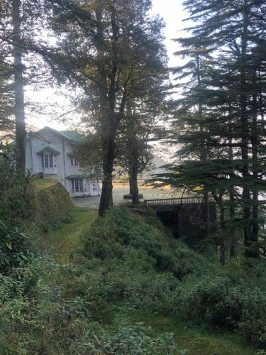 una casa en una colina con árboles y un puente en Shivoham valley view camps, en Mussoorie