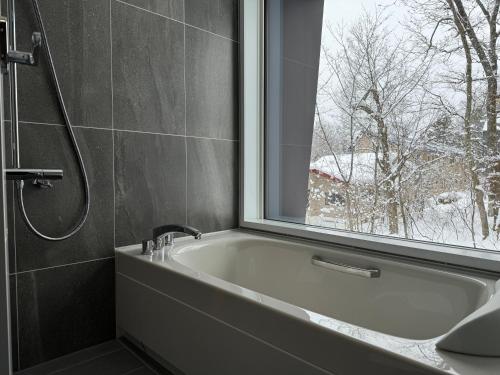 a bathroom with a bath tub and a window at Chalet Infinity by The Hakuba Collection in Hakuba