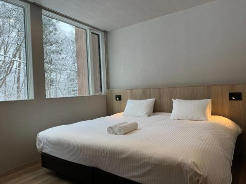 a bedroom with a bed with two towels on it at Chalet Infinity by The Hakuba Collection in Hakuba