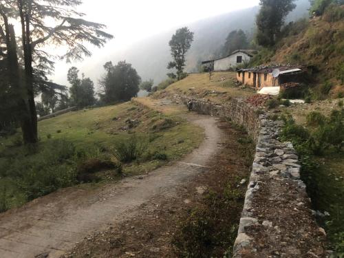 a dirt road with a house on a hill at Shivoham valley view camps in Mussoorie