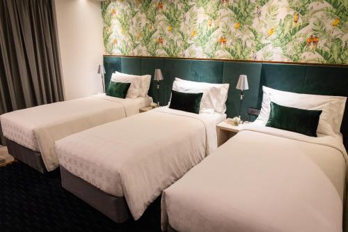 three beds in a hotel room with a wallpaper at Hotel Clover Asoke - SHA Extra Plus in Bangkok