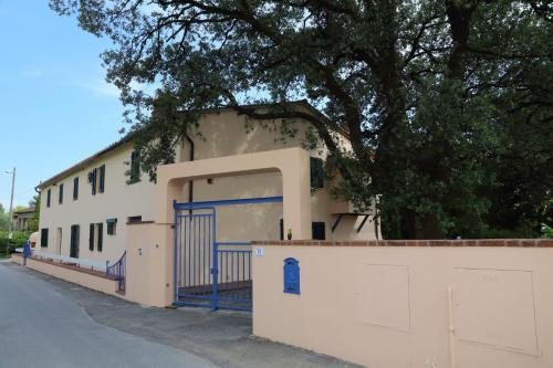 a white building with a blue gate and a tree at Al Vecchio Leccio in Pistoia