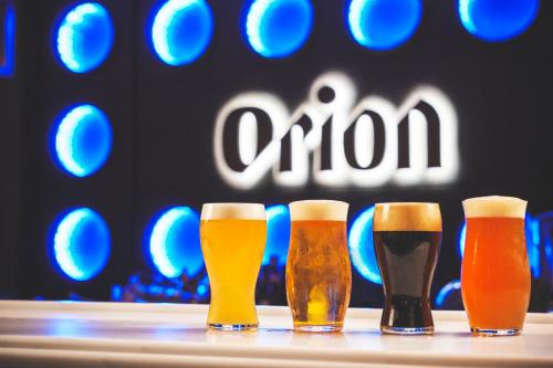 four glasses of beer on a table in front of an ooni sign at Orion Hotel NAHA in Naha
