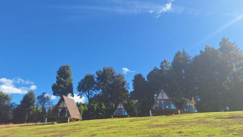 een groep cottages bovenop een grasheuvel bij Cabañas Keikary in Valle de Bravo