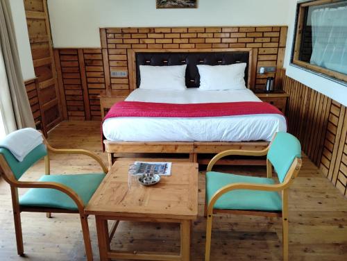 een slaapkamer met een bed en 2 stoelen en een tafel bij Hotel CM Palace - Pure Vegetarian 