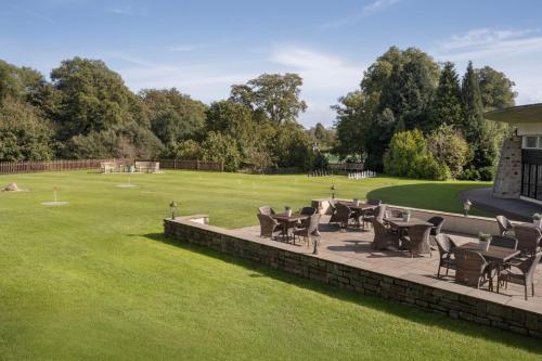 a patio with chairs and tables on a lawn at Delta Hotels by Marriott St Pierre Country Club in Chepstow