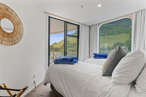 a bedroom with two beds and a large window at Oceanside Sunset Views in Mount Maunganui