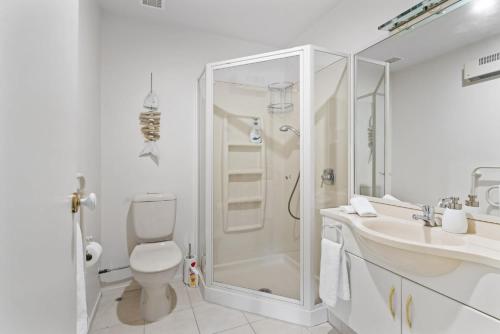 a white bathroom with a shower and a toilet at Oceanside Sunset Views in Mount Maunganui