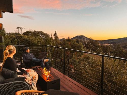 a man and woman sitting on a deck watching the sunset at Cedar Hot Tubsunset Viewsluxurious in Julian