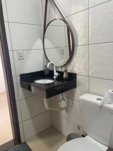 a bathroom with a sink and a mirror and a toilet at Casa de praia Jauá in Camaçari