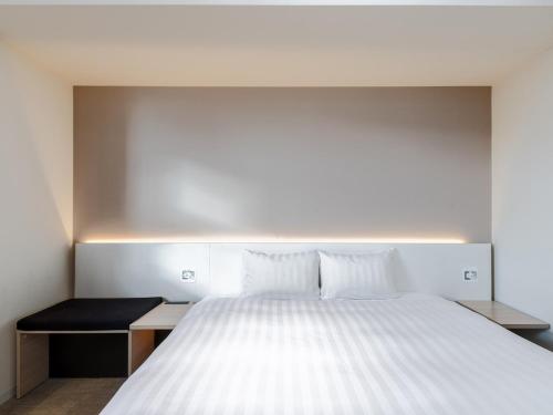 a bedroom with a large white bed and a desk at The OneFive Sendai in Sendai