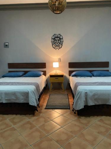 a bedroom with two beds and a table with a lamp at Casa Ceiba/Dpto. entero cerca del Centro Histórico in Oaxaca City