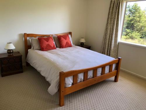 a bedroom with a bed with red pillows and a window at Jennifer's Cottage in Reidston