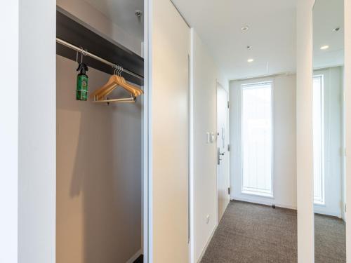a hallway with white walls and a door with a closet at The OneFive Sendai in Sendai
