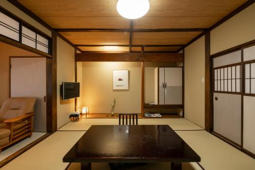 a living room with a table and a tv at 岩井温泉　岩井屋 in Iwamicho