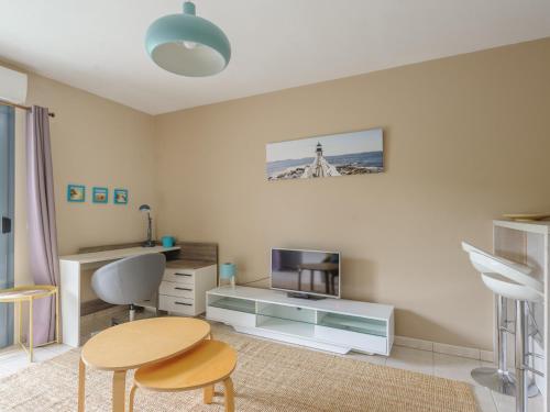 - un salon avec une table, une télévision et un bureau dans l'établissement Studio ensoleillé au bord de mer avec balcon et parking, proche centre et plage - La Rochelle - FR-1-535-51, à La Rochelle