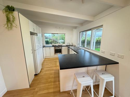 a kitchen with a black counter and two stools at Miami one one in Oneroa