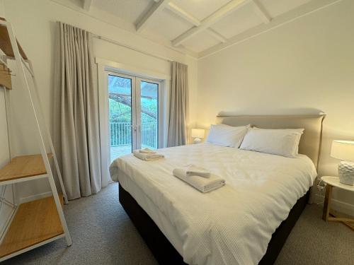 a bedroom with a large white bed with a window at Miami one one in Oneroa